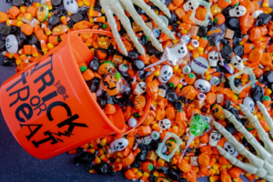 Skeleton hands reach for Halloween candy that’s scattered over a table